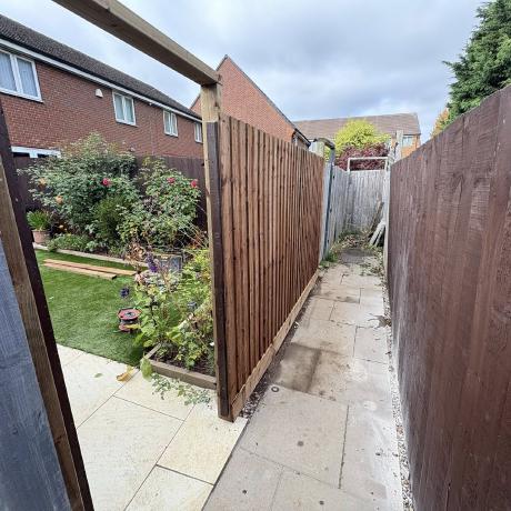 New closeboard fence panels installed along a paved side passage