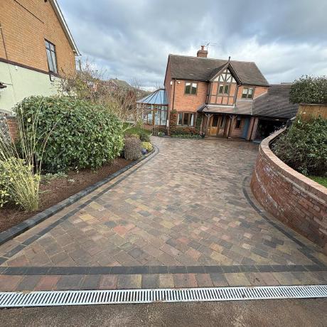 Tumbled block-paved driveway with charcoal border and curved brick wall in Kingswinford
