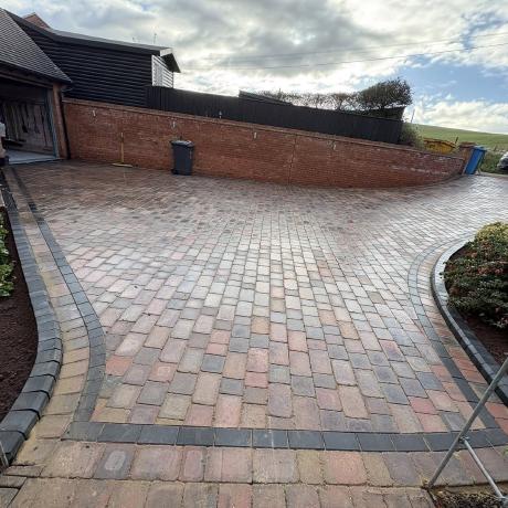 Curved block-paved driveway with charcoal border and brick boundary wall