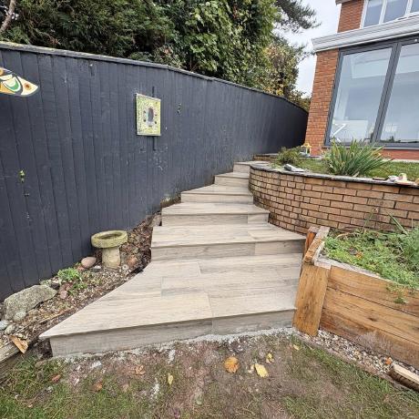 Porcelain garden steps with brick planter walls on a landscaped slope