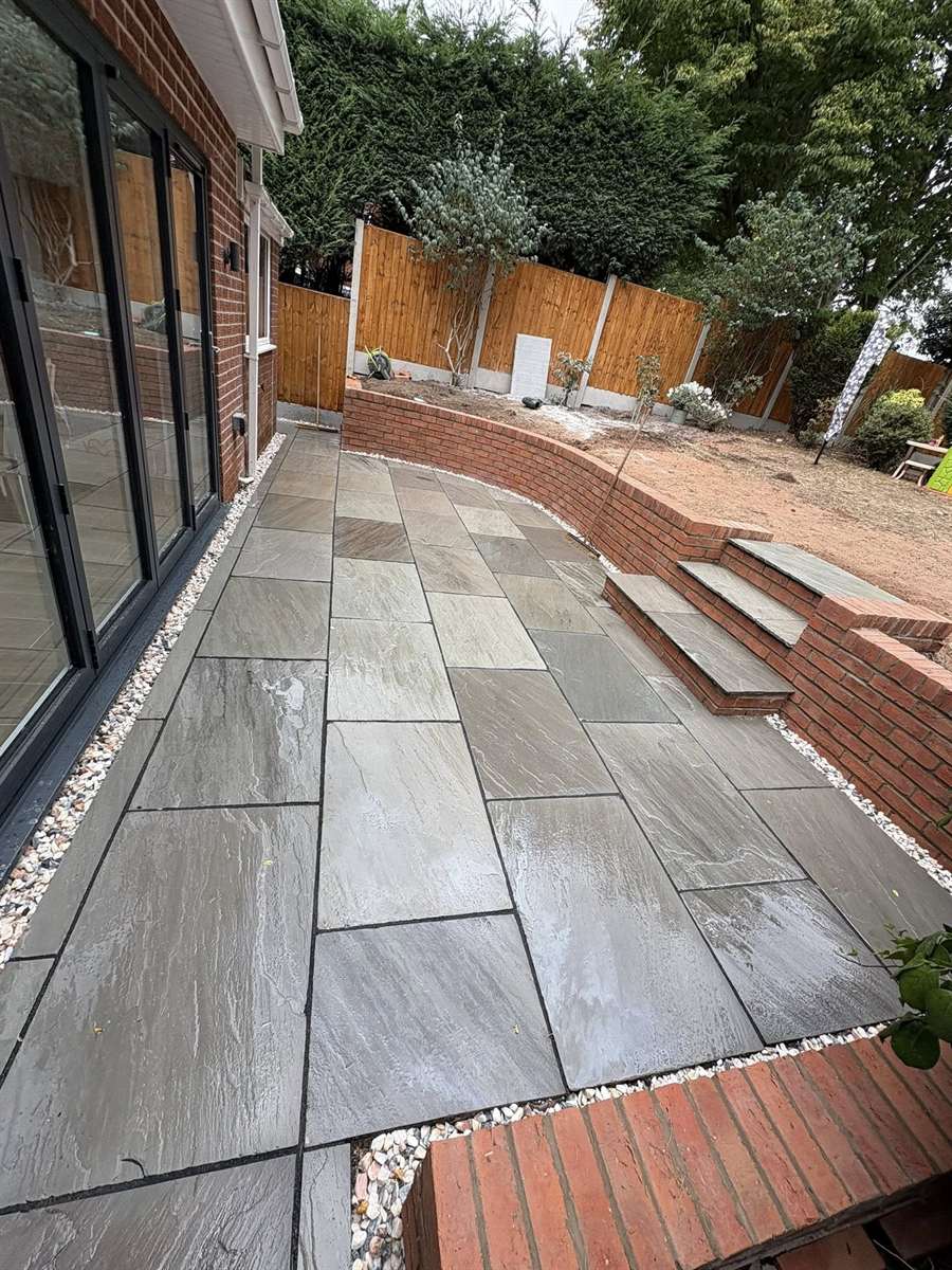 Indian sandstone patio and brick retaining wall built in a West Midlands garden